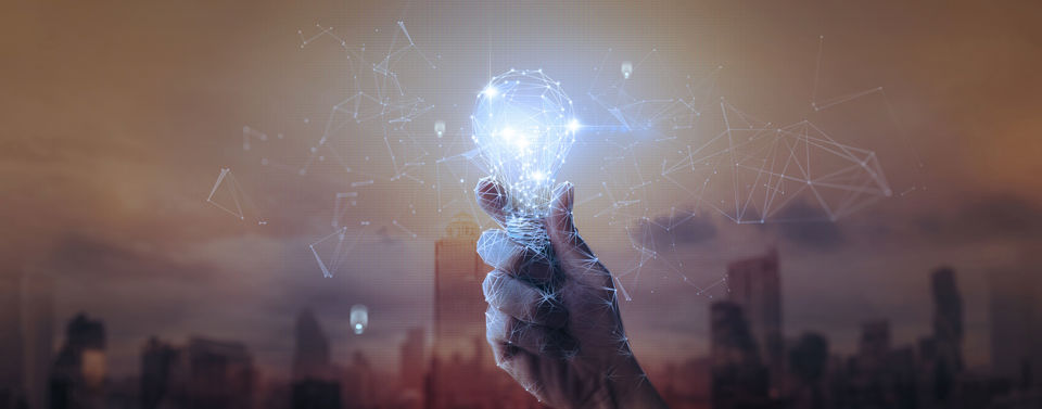 Innovation - eine Hand hält eine Glühbirne aus vernetzten, leuchtenden Linien