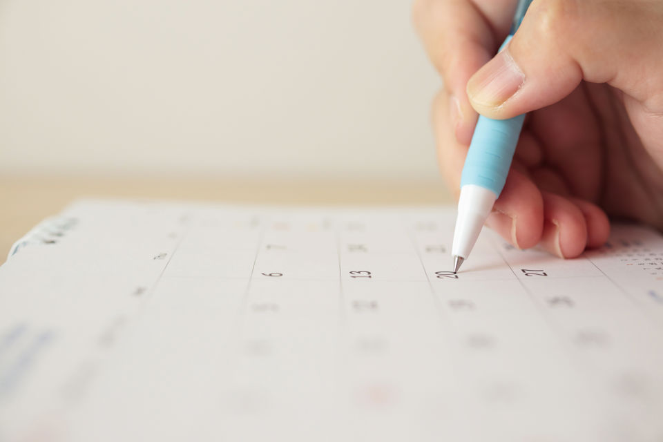 Frau markiert etwas im Kalender auf einem Tisch