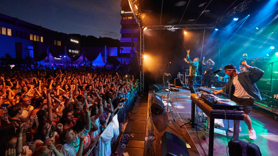 Eine Band spielt auf einer Bühne vor Zuschauern beim Festival Sommer im Park