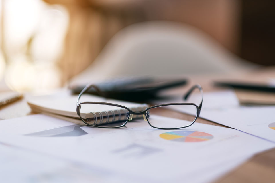 Brille liegt gemeinsa mit unterschiedlichen Notizen auf einem Bürotisch