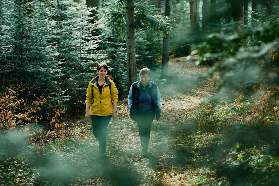 St.Galler Finanzberatung: Eine junge Frau geht mit ihrer Mutter im Wald spazieren