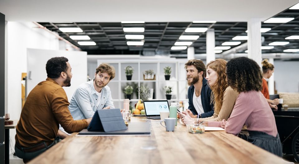 Ein junges, innovatives Team hält in einem Open Space Büro eine Besprechung ab