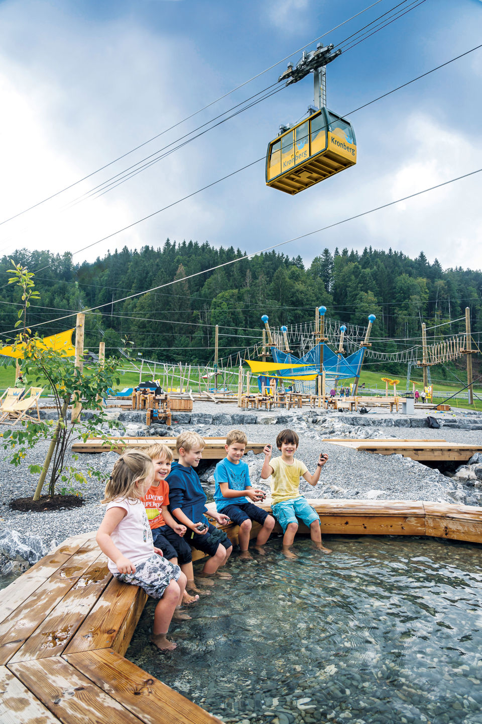 Kinder baden ihre Füsse in einem Becken unter der Kronberg Seilbahn