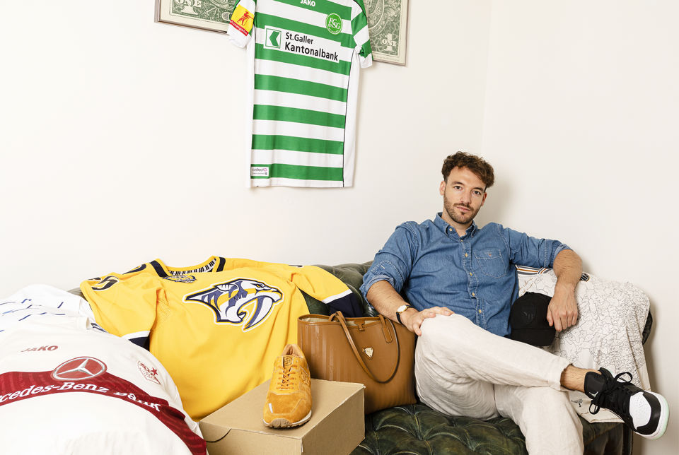 David Gasser, CEO von CollectID, auf einem Sofa neben Collectibles wie Trikots, Taschen und Turnschuhen