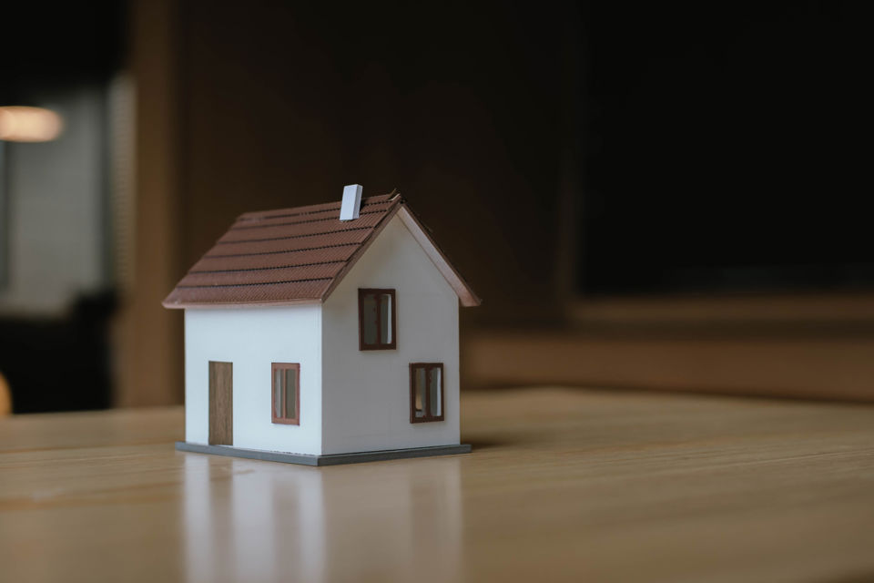 Symbolbild für Liegenschaften: Ein Miniaturhaus auf einem Tisch
