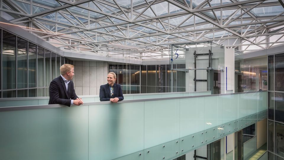 Zwei Mitarbeitende der SGKB stehen auf einer Glasbrücke im Hauptsitz der St.Galler Kantonalbank