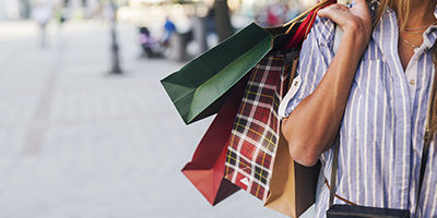 Promobild Shopping - Eine Frau trägt mehrere Einkaufstaschen über der Schulter