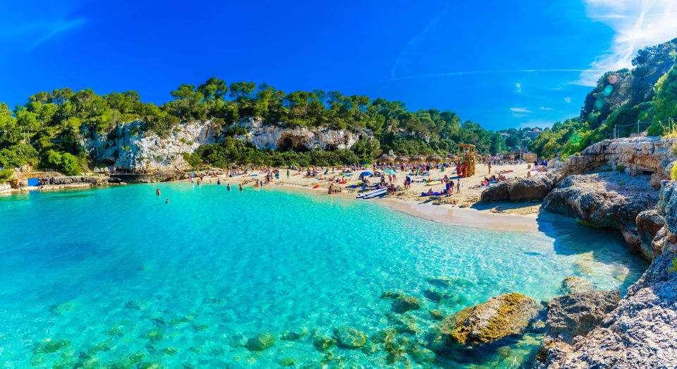 Ferientipps - Aussicht auf einen Sandstrand in einer Bucht bei Sonnenschein